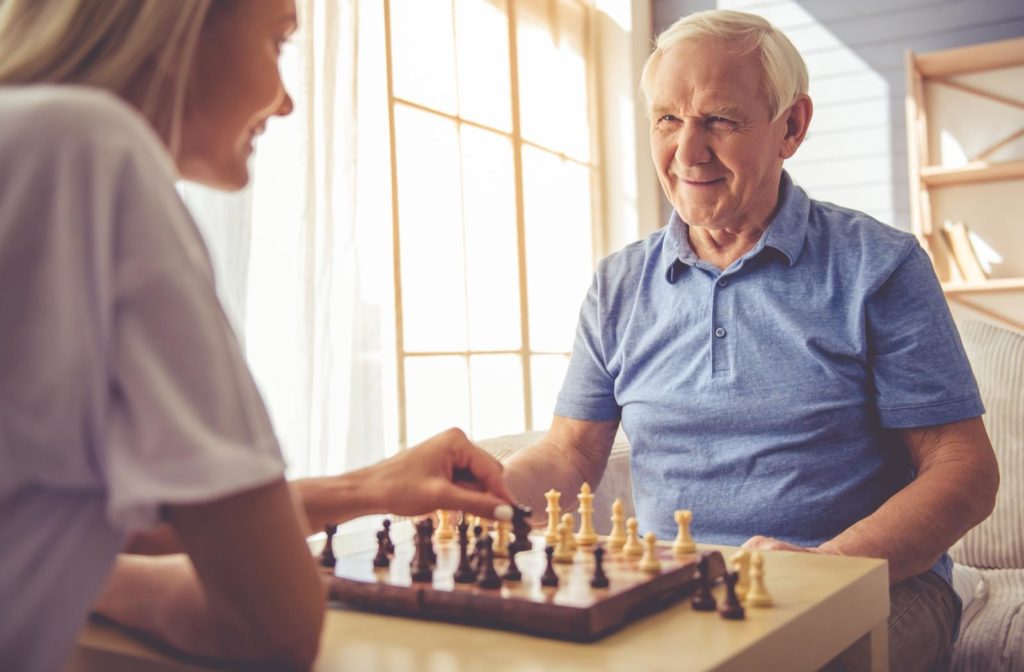 Senior at home playing chess with his daughter in order to support healthy cognition