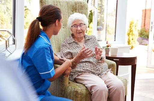 A female nurse talking to an older female memory care patient.