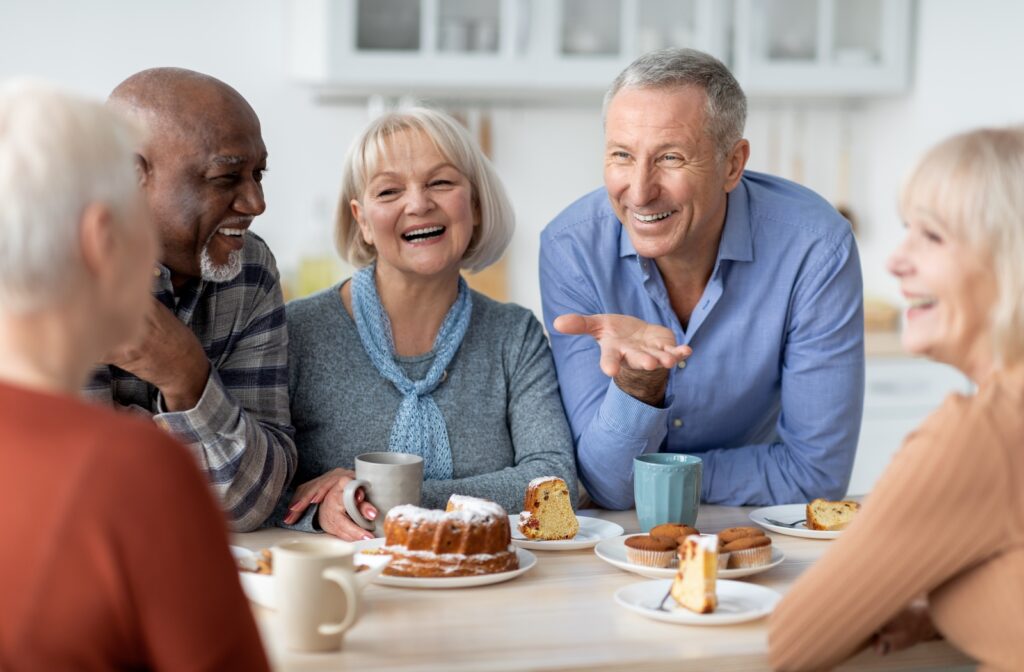 A group of residents sitting around a table and laughing while enjoying coffee and cake.