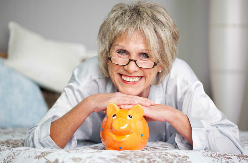 A happy mature woman leading on her orange piggy bank.