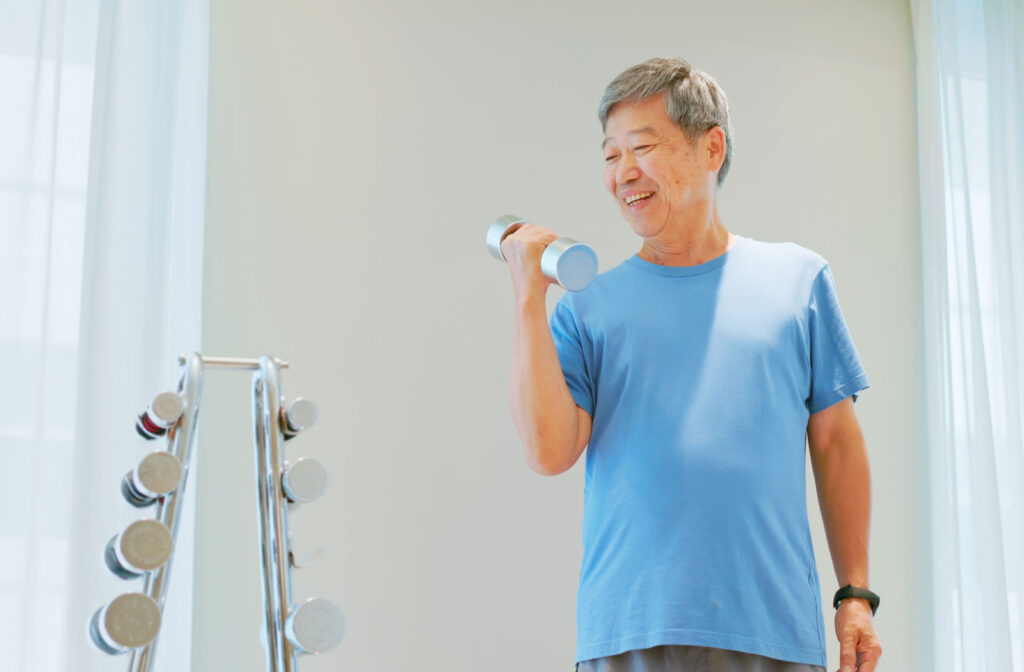 A smiling senior man exercising with dumbbells.
