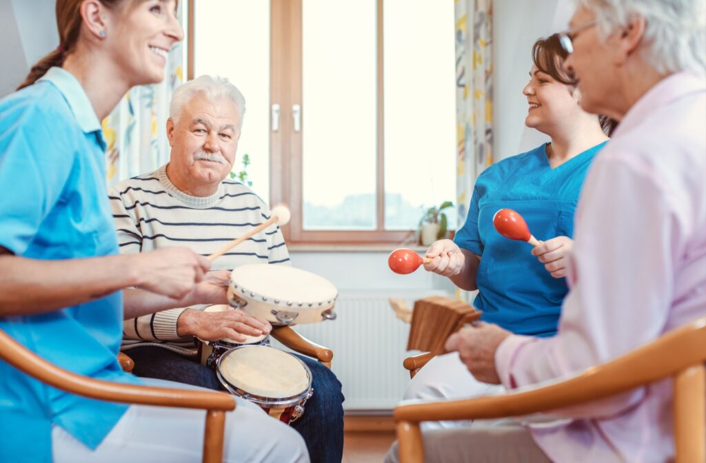 2 seniors and 2 nurses sit in a circle holding maracas, tambourines, & drums.