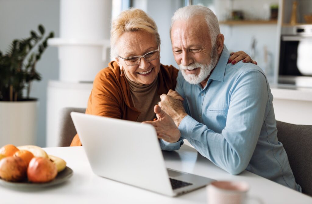 Couple smiling at computer screen.