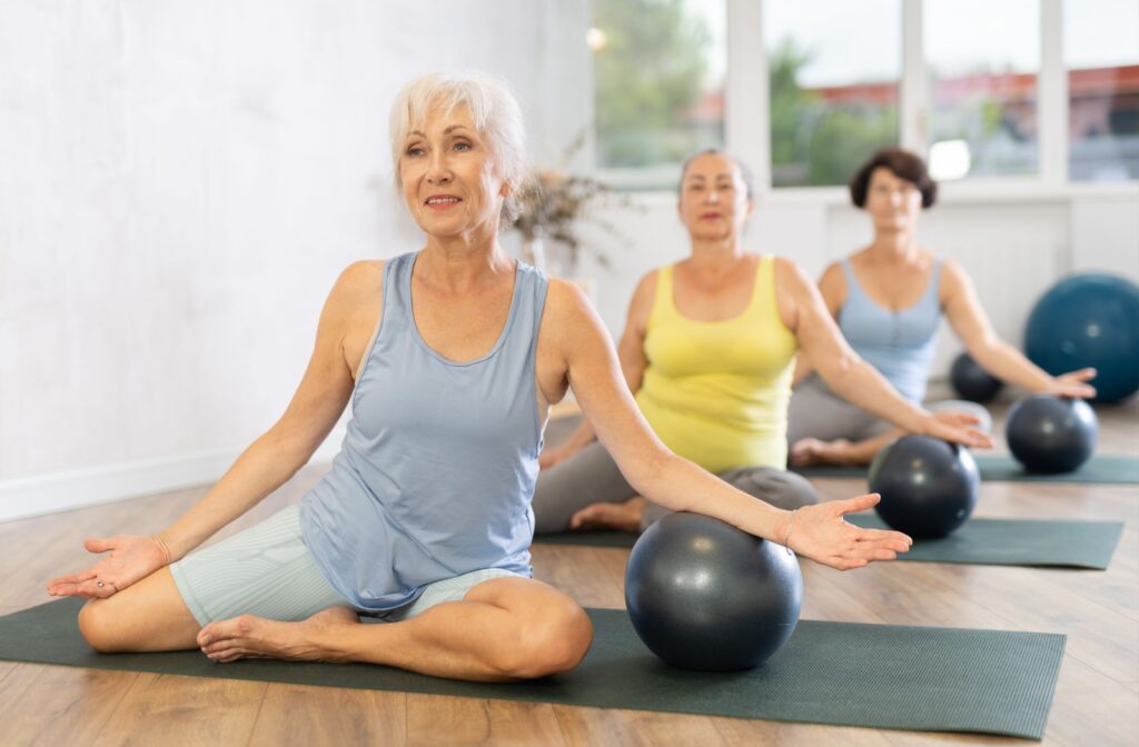 Group of seniors in a Pilates class using exercise balls on mats improving core strength balance and senior fitness.