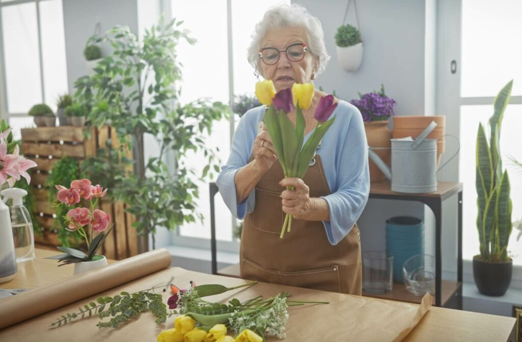 Senior woman arranges colorful tulips in a sunlit flower shop