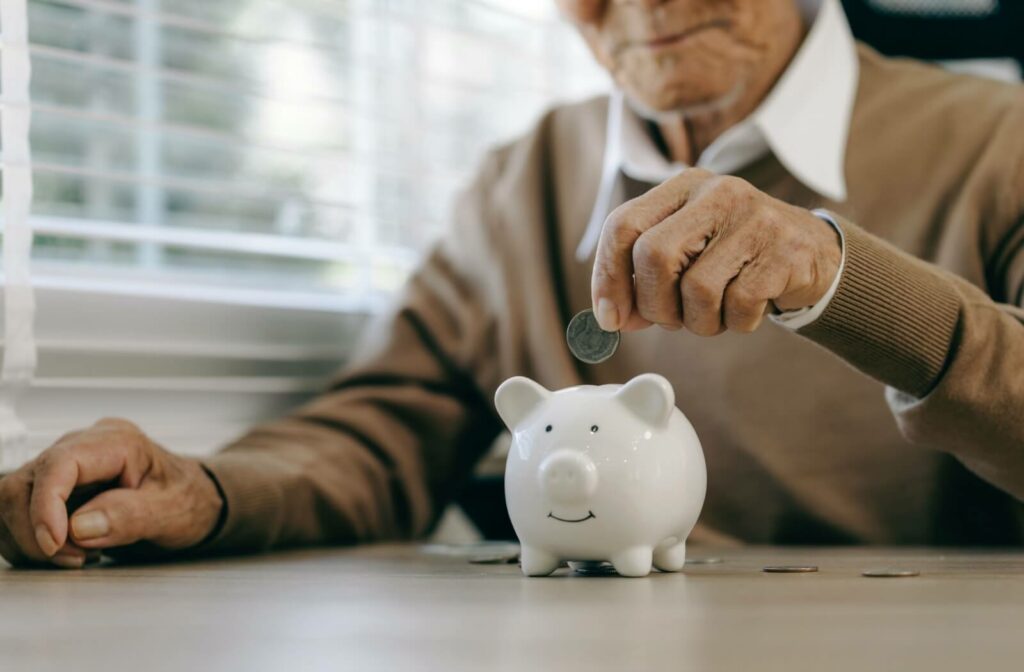 A senior prepares to drop a coin into a piggy bank, symbolizing saving for retirement and preparing for the future