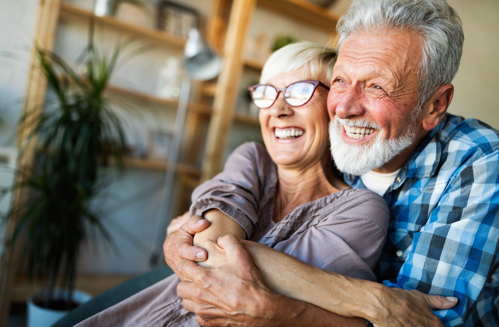 A senior couple embrace and smile together after having just moved into an independent living community.
