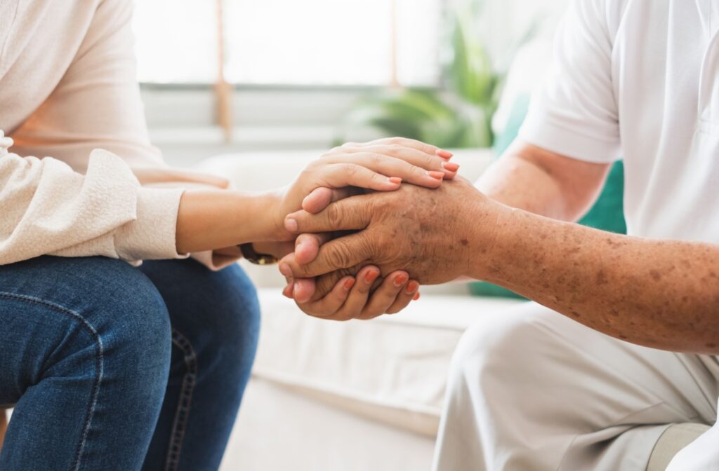 A caregiver grasps the hands of a senior resident.