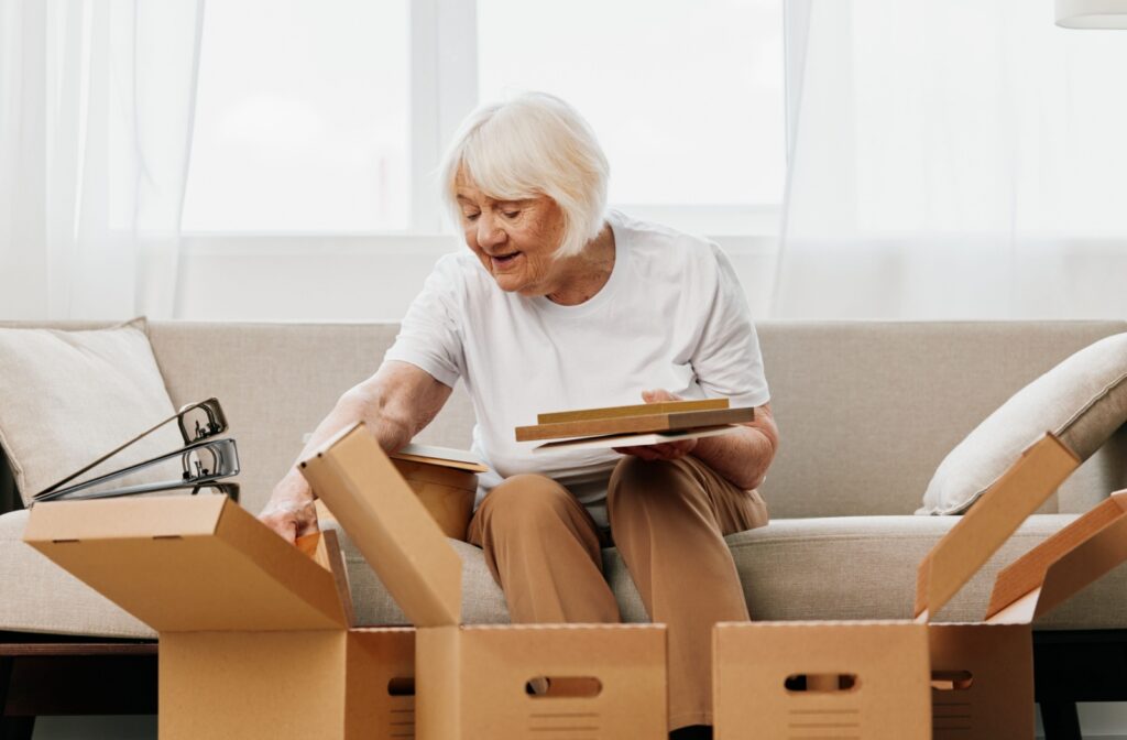 A senior packs cardboard boxes of photos and files while packing up their home to downsize.