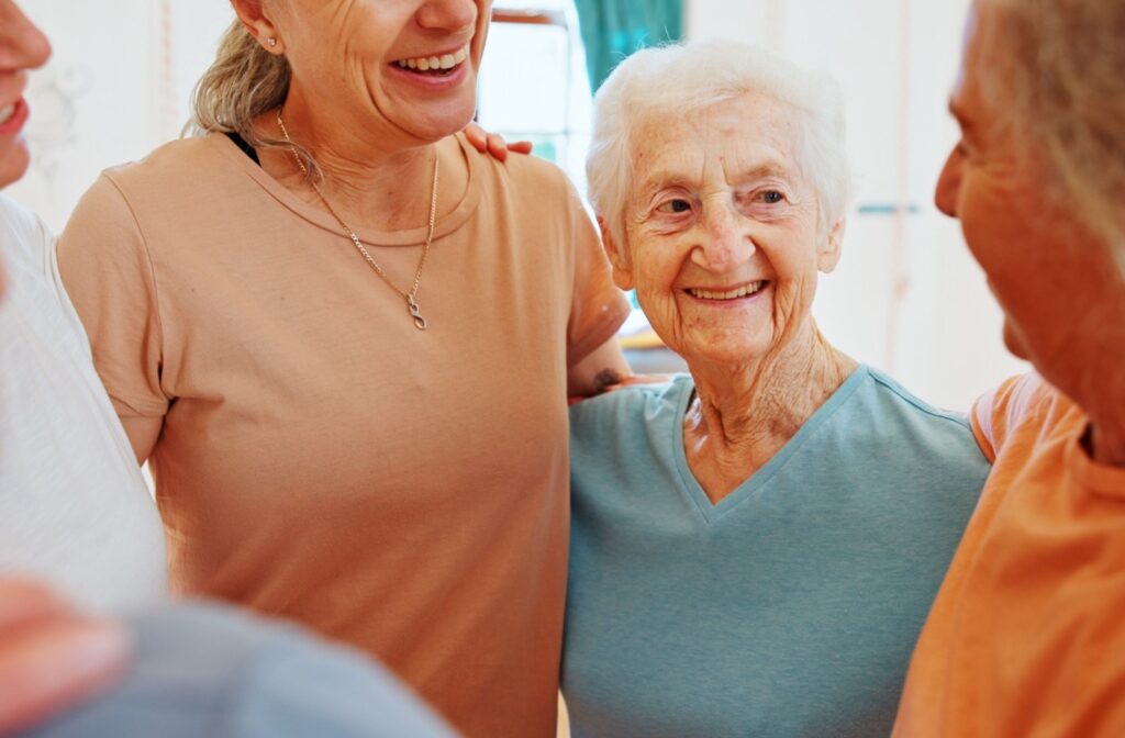 A senior resident smiles as they are surrounded by friends during a social program at a senior living community.