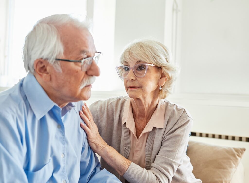 A senior couple embracing, hugging, and comforting each other. The woman is looking closely at the man with passion.